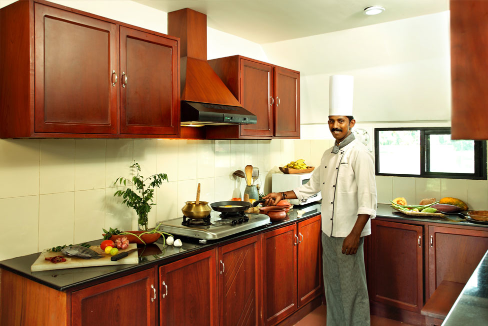 Chef cooking in the houseboat kitchen Kerala India;